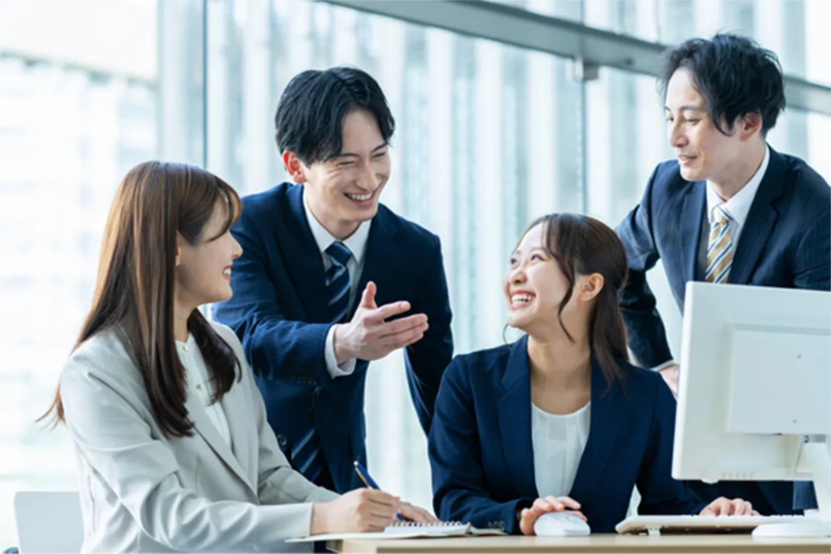 パソコンを前に笑顔で会話するビジネスシーン